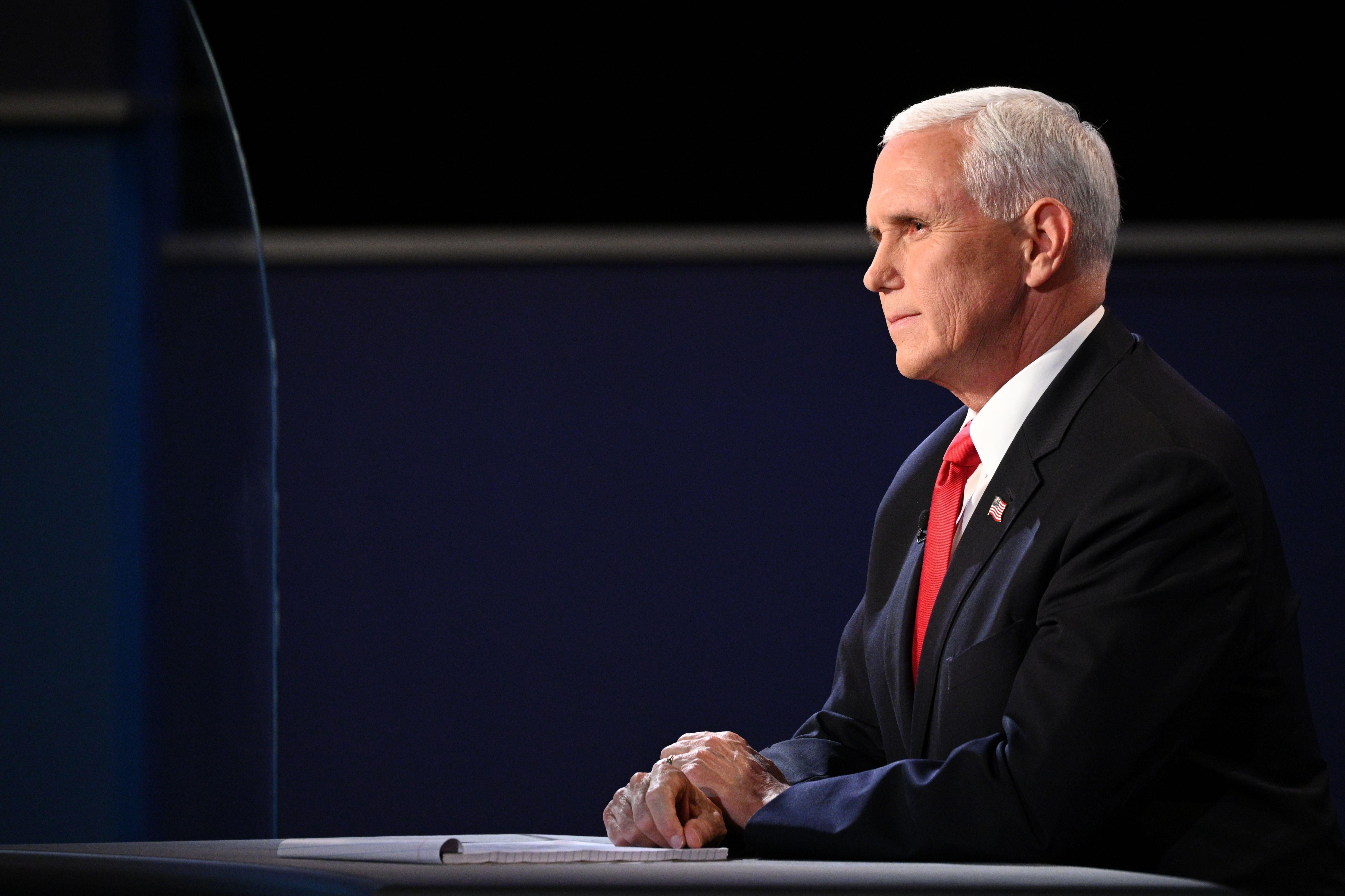 Pence sits at his desk at the debate stage.