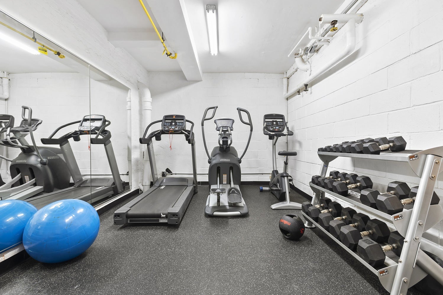A small gym with weights, a treadmill, an exercise bike, and a stair climber