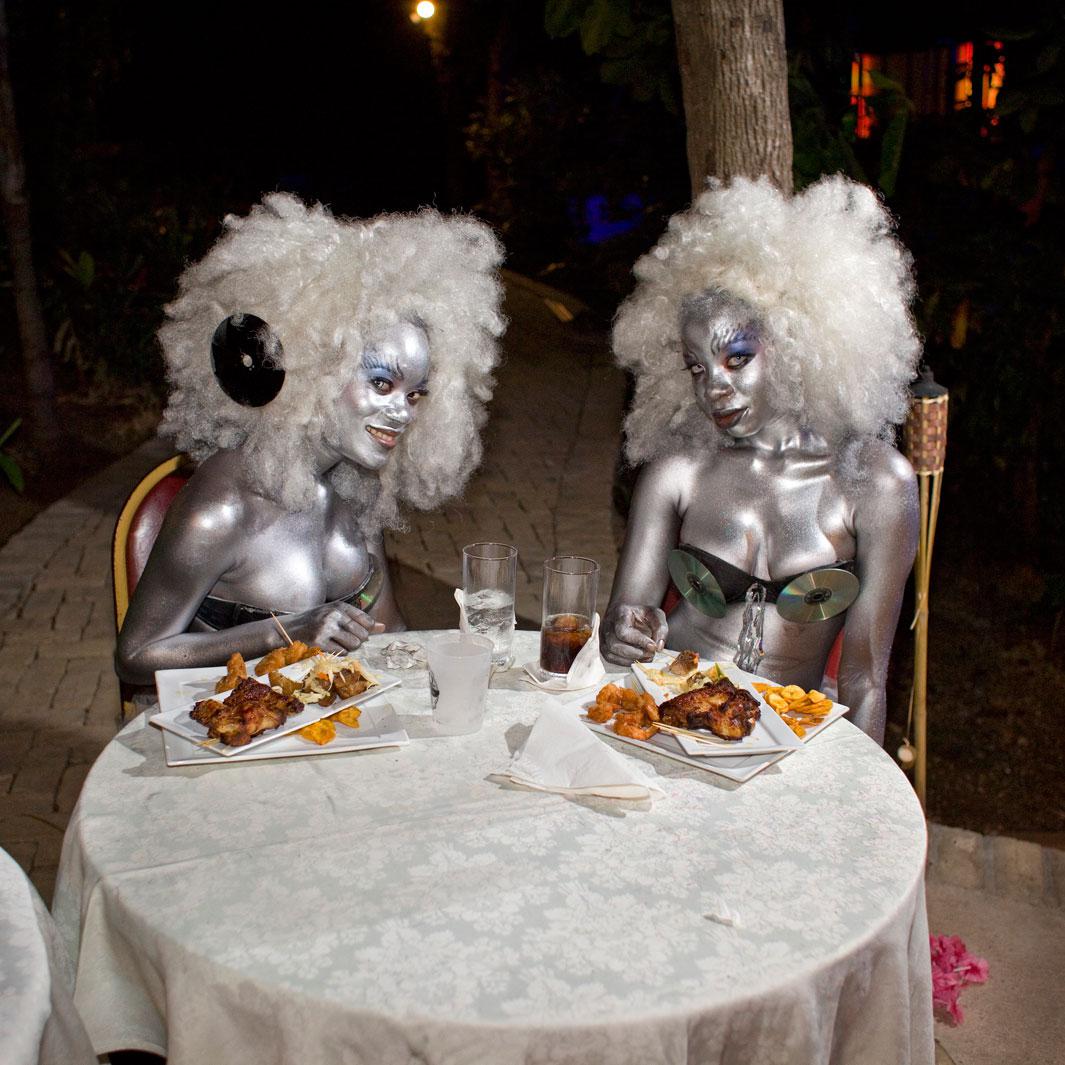 At the Karibe Hotel, above Port-au-Prince, two go-go girls dig into fried chicken after dancing for hours at the concert of a local singer, J Perry. Juvènat,  Pétion-ville, Haiti.