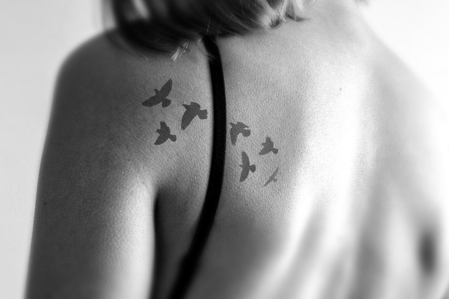 A woman with a tattoo on her shoulder of seven blackbirds.