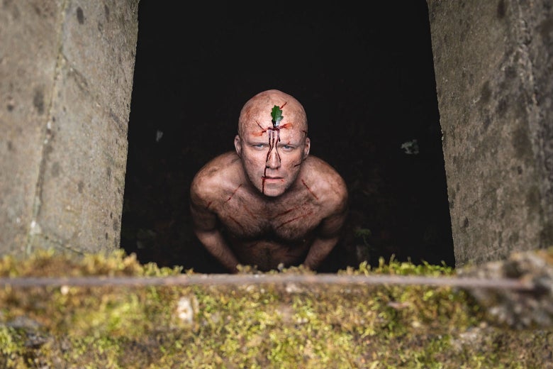 A bloodied, naked man in a hole.