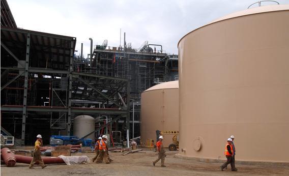 Construction workers walk by the demineralised and raw water tanks.