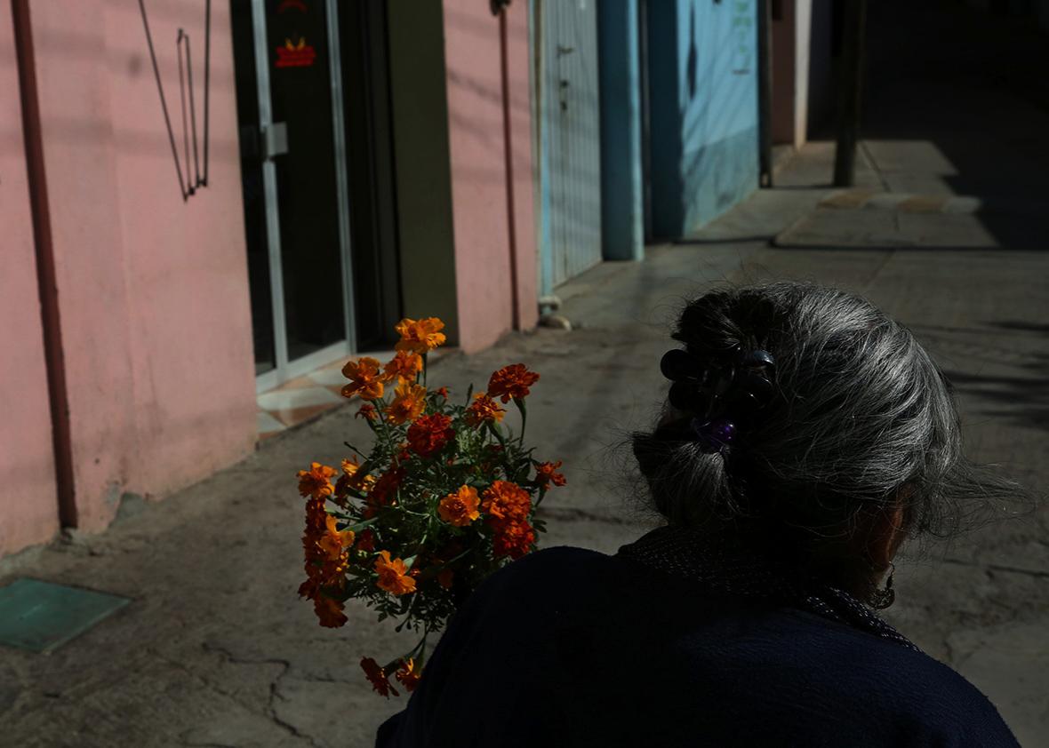 Teresa Raymundo walks to a funeral with a bundle of flowers in San Juan del Rio, Oaxaca, Mexico.