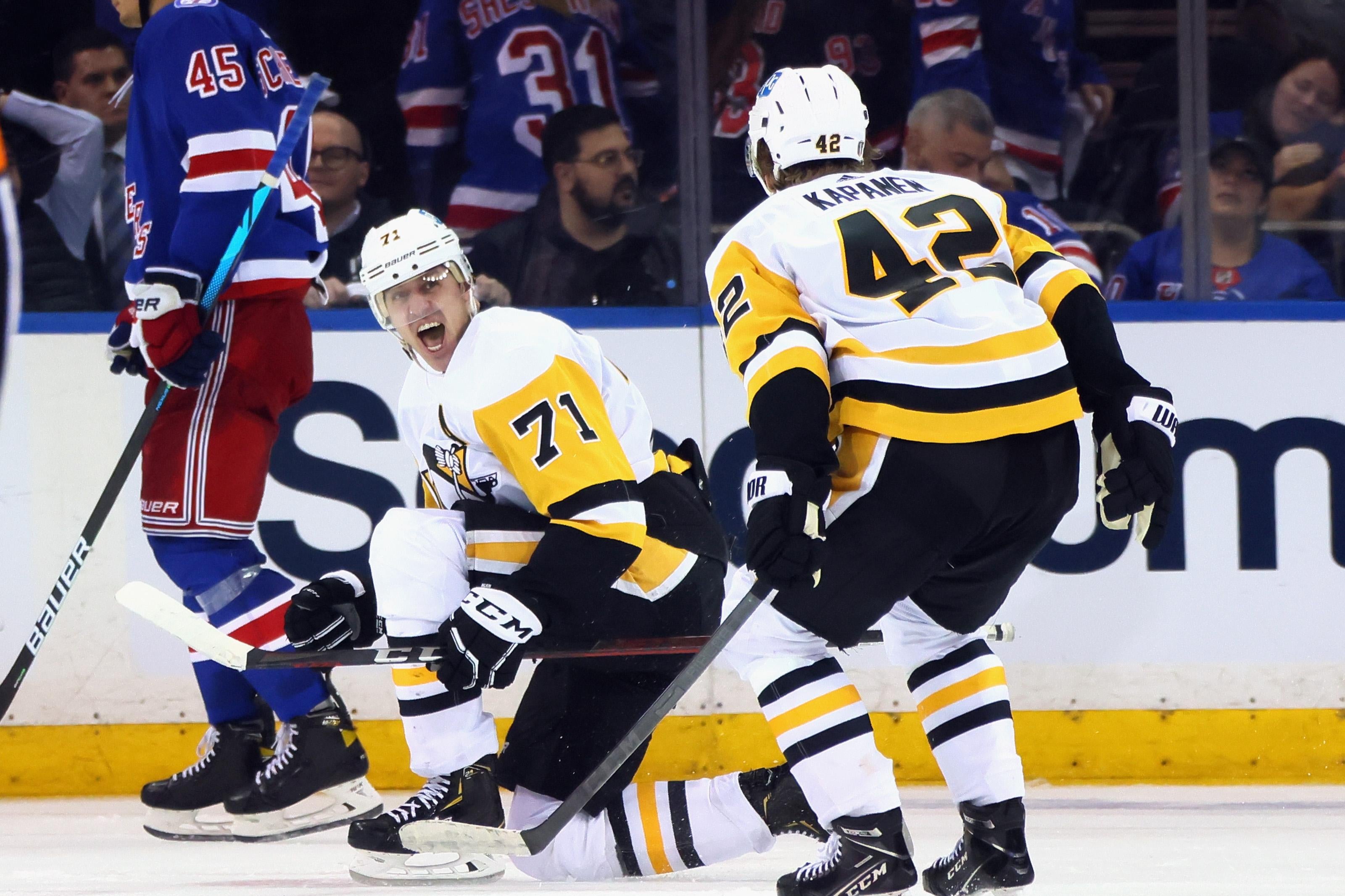 Malkin crouches and screams in celebration on the ice, looking at his teammate Kasperi Kapanen whose back is turned, as a New York Ranger skates dejectedly in the background