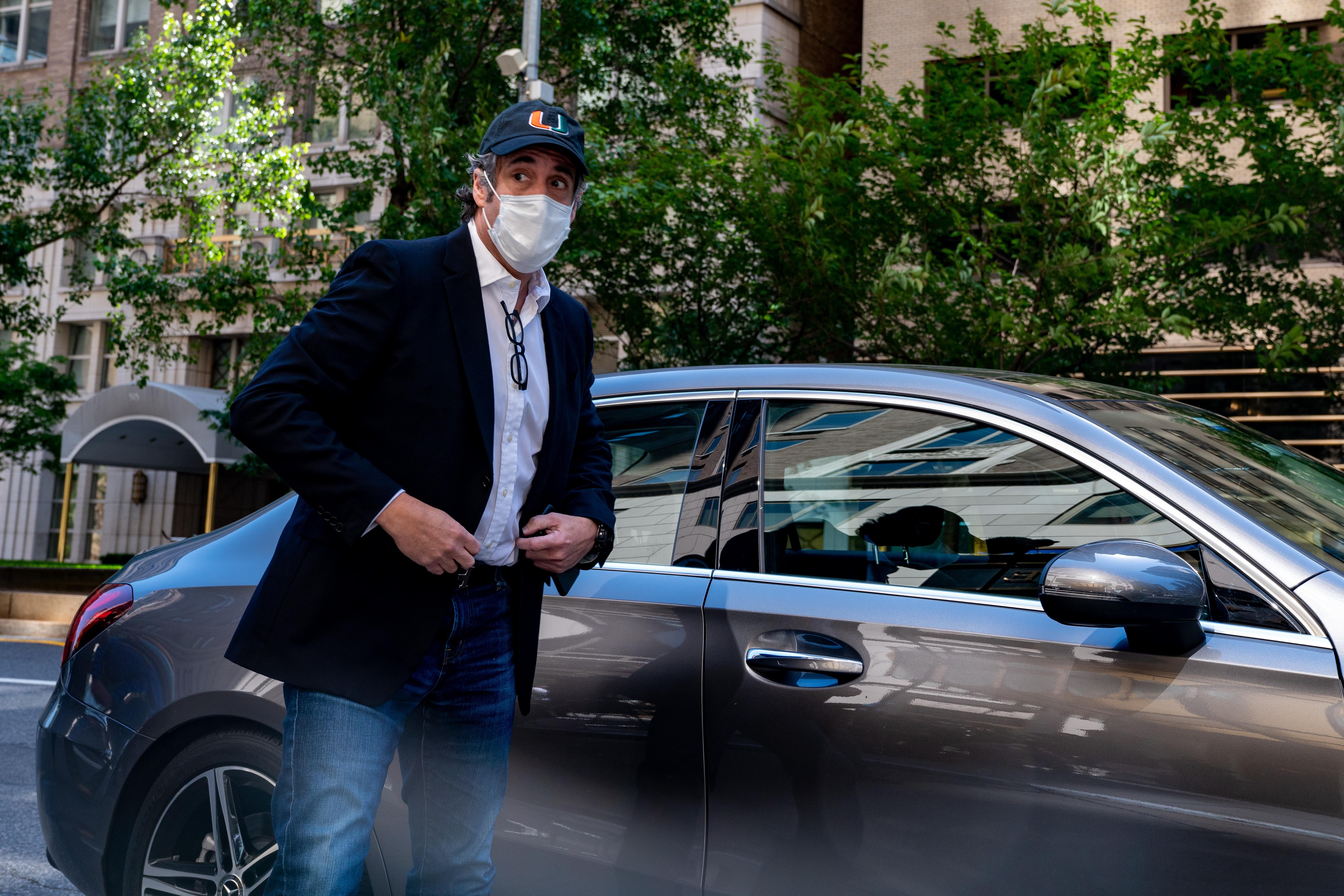 Michael Cohen is seen wearing a face mask next to a car.