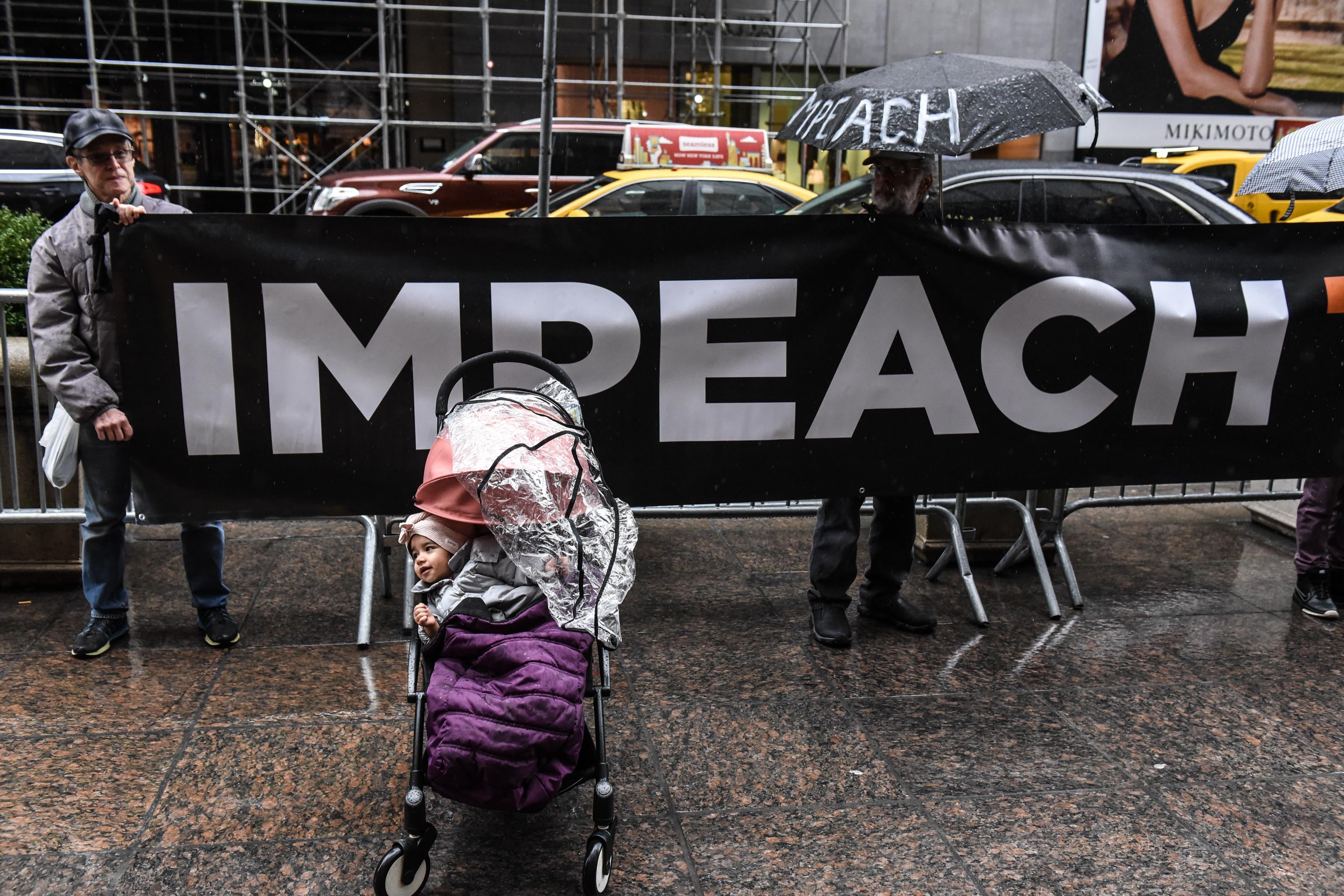 A baby sits in a stroller in front of a sing that reads "impeach" while a protest group called Rise and Resist holds a protest in front of Trump Tower demanding that The Trump Organization executives "cooperate with Congress" on March 21, 2019 in New York City.