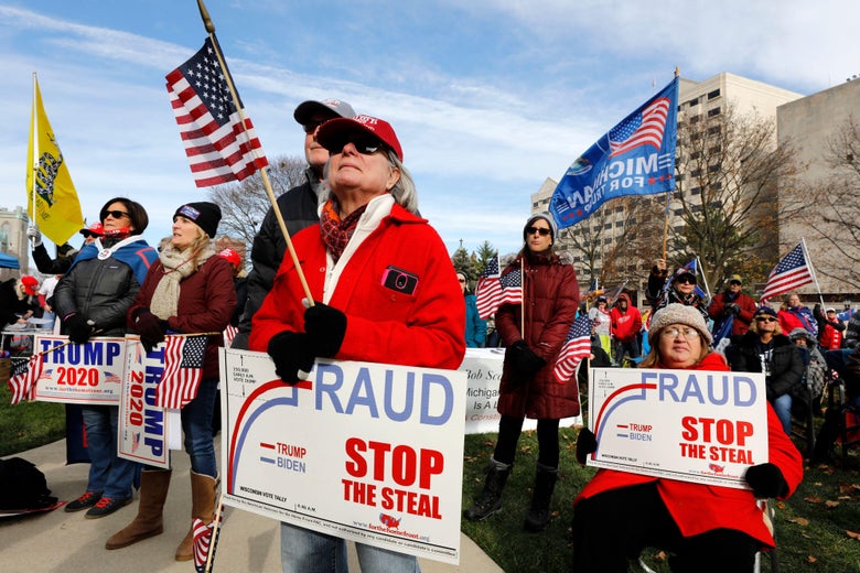 A crowd of Trump supporters holding "Stop the Steal" and "Trump 2020" signs and American flags