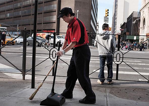 A McDonald's employee sweeps up in front of a restaurant.