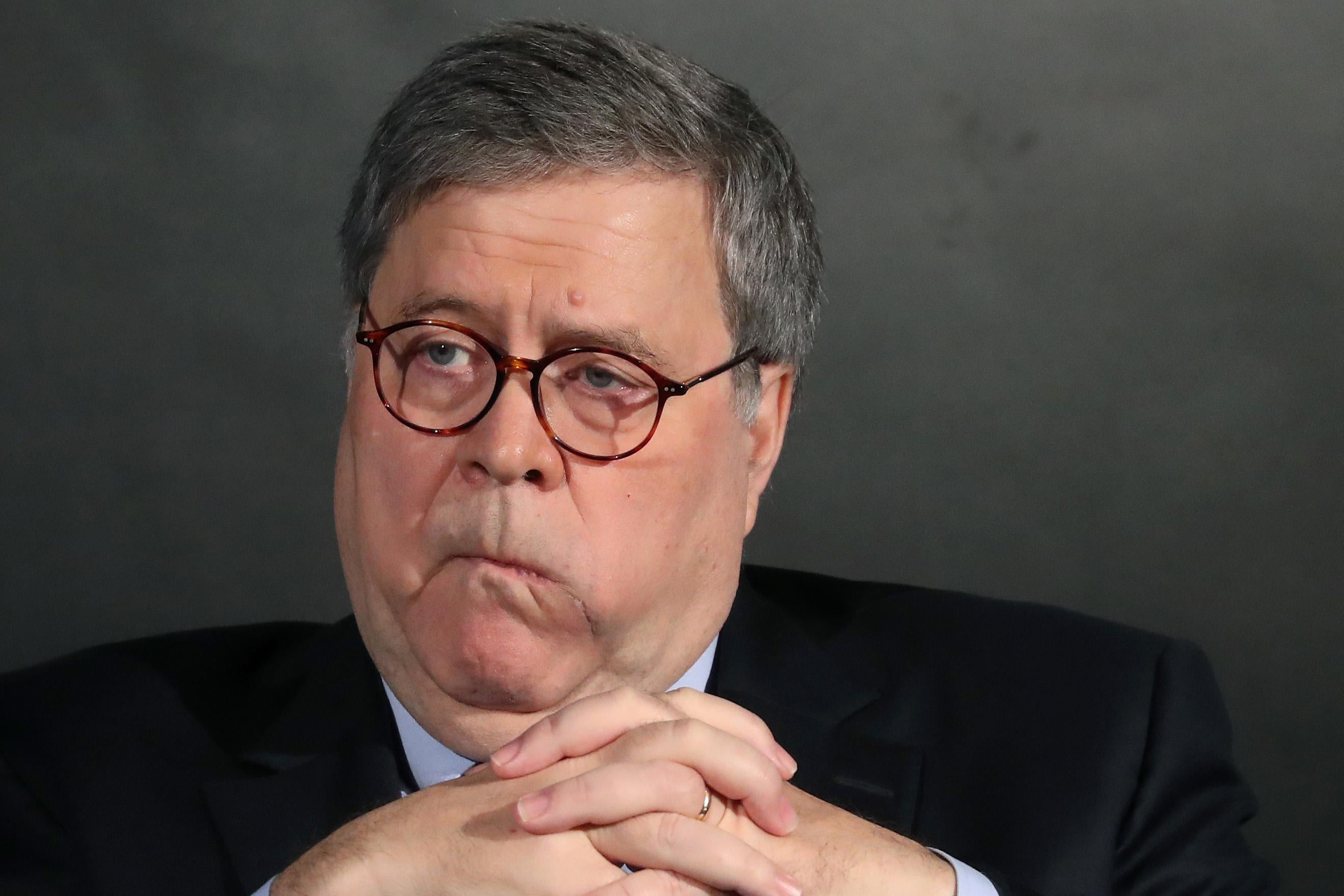 William Barr pursing his lips and holding his hands together in a way that makes him look particularly sinister.