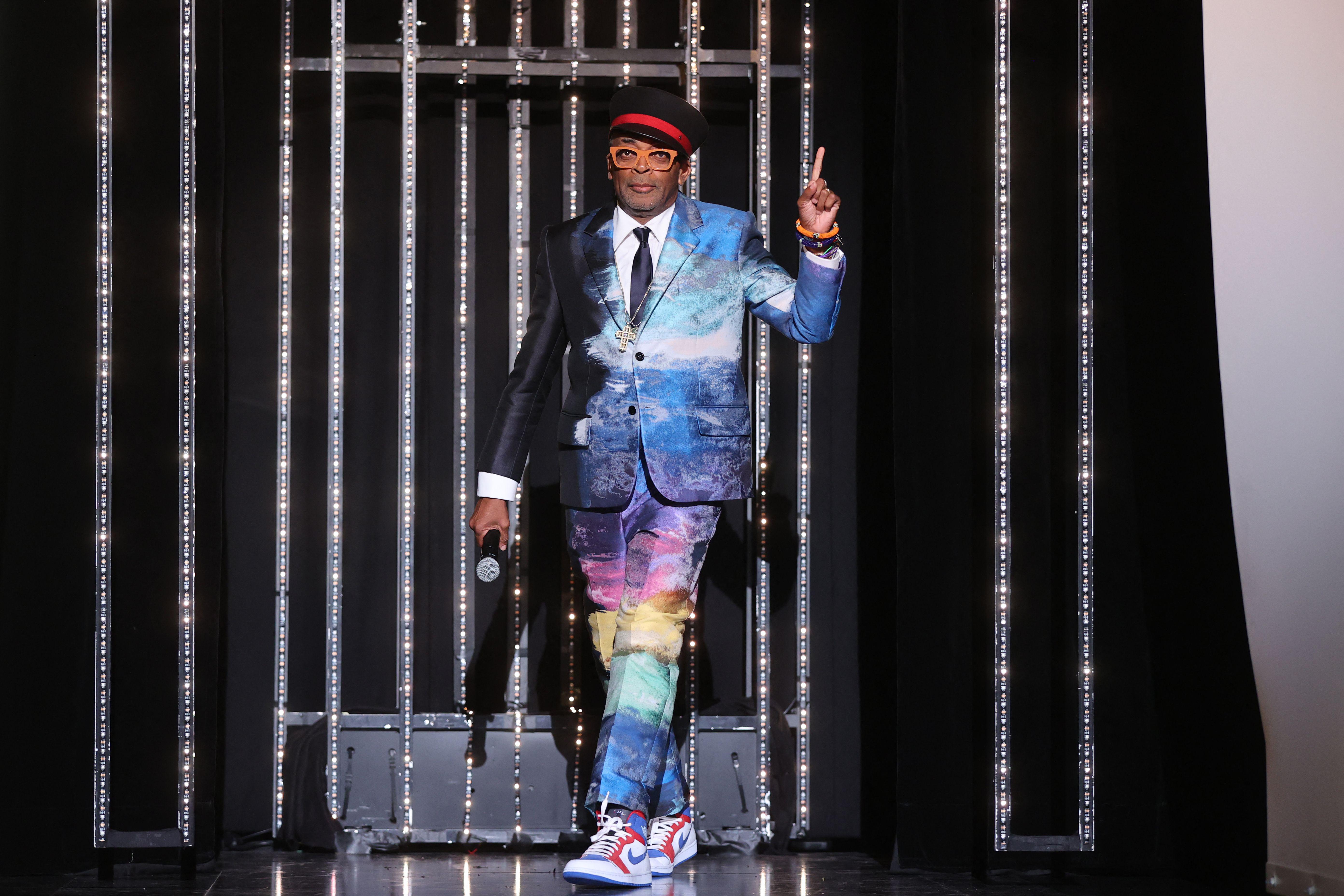 Spike Lee walks out on a stage wearing a suit of rainbow colors.