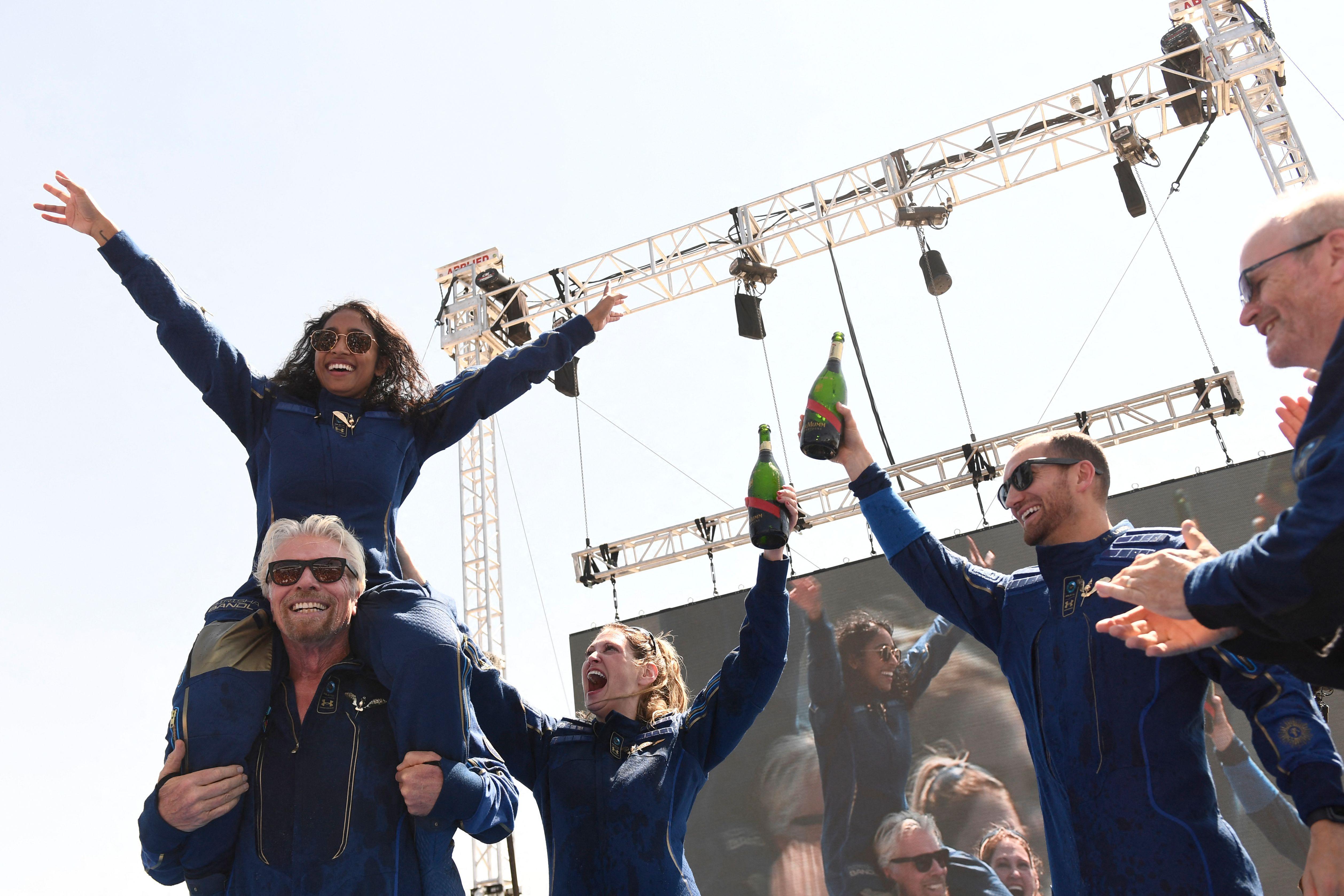 Virgin Galactic founder Sir Richard Branson(L), with Sirisha Bandla on his shoulders, cheers with crew members after flying into space aboard a Virgin Galactic vessel, near Truth and Consequences, New Mexico on July 11, 2021.