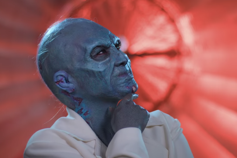 Woman dressed as a gray decaying zombie.