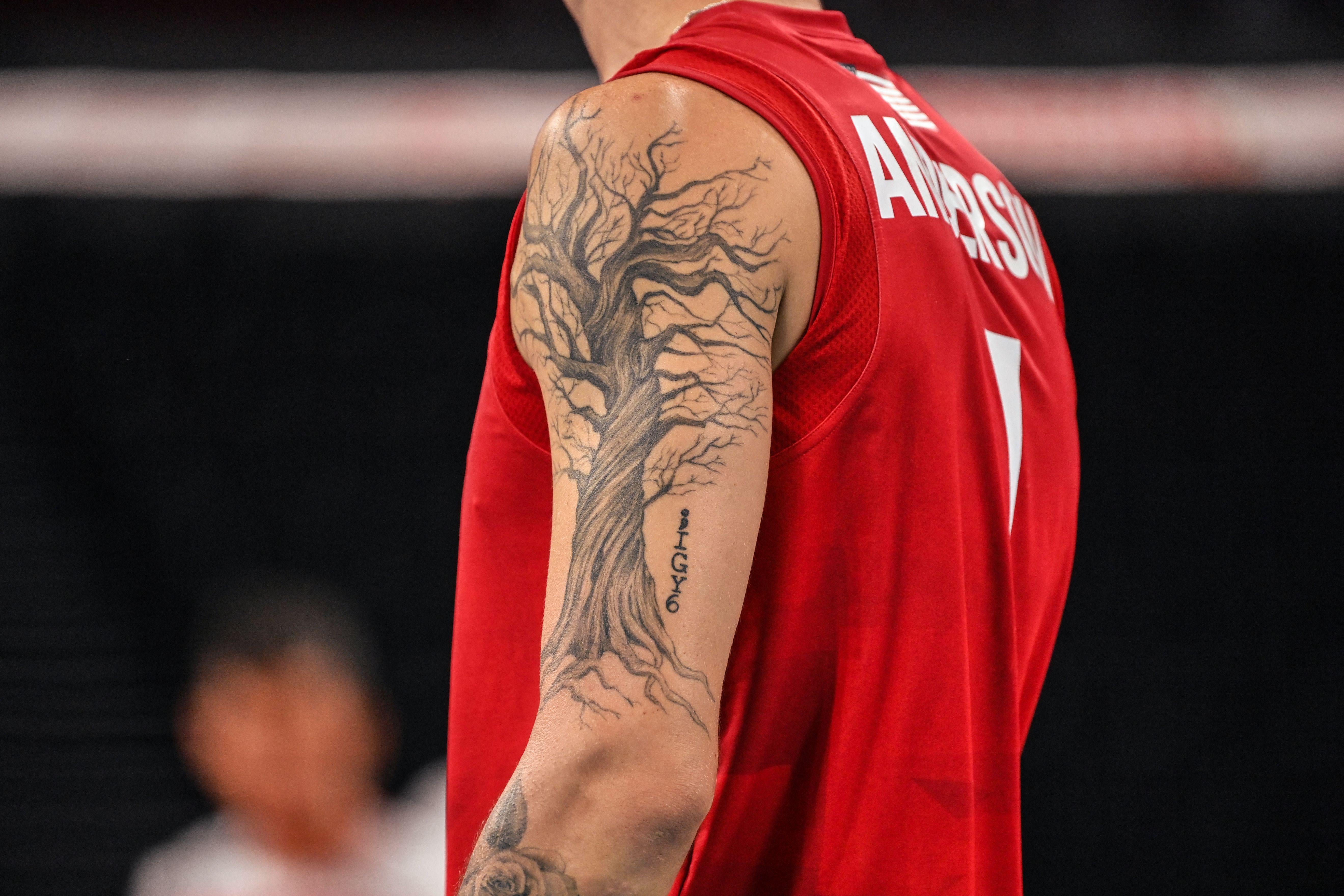 Anderson's left arm with a large twisted leafless tree tattoo on it, in tank uniform for indoor volleyball