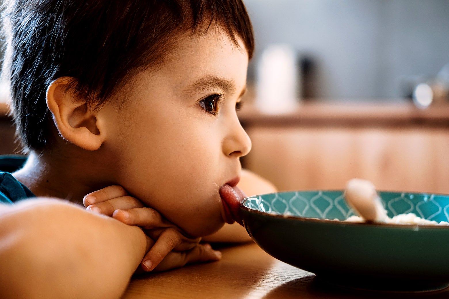 A child sits next to a bowl of food.
