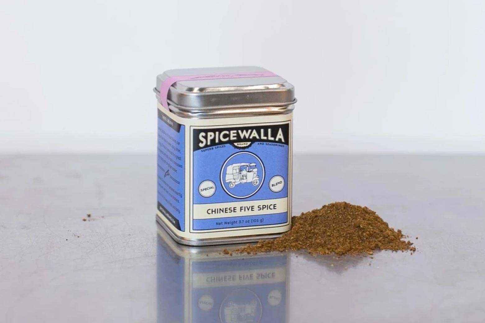 Spice can with a pile of five-spice powder beside it on a metal surface