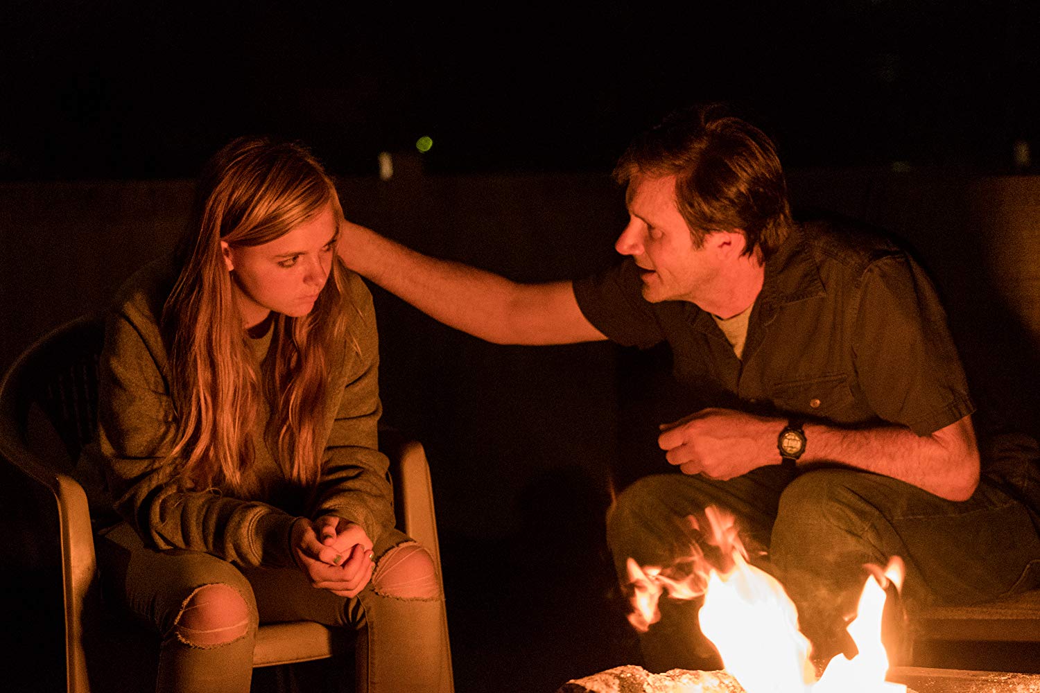 In a still from Eighth Grade, Elsie's father tries to comfort her as they sit in front of a campfire.