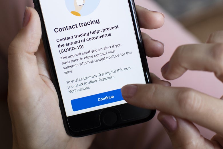 A person's hands hold a phone displaying an app that says "Contact Tracing."