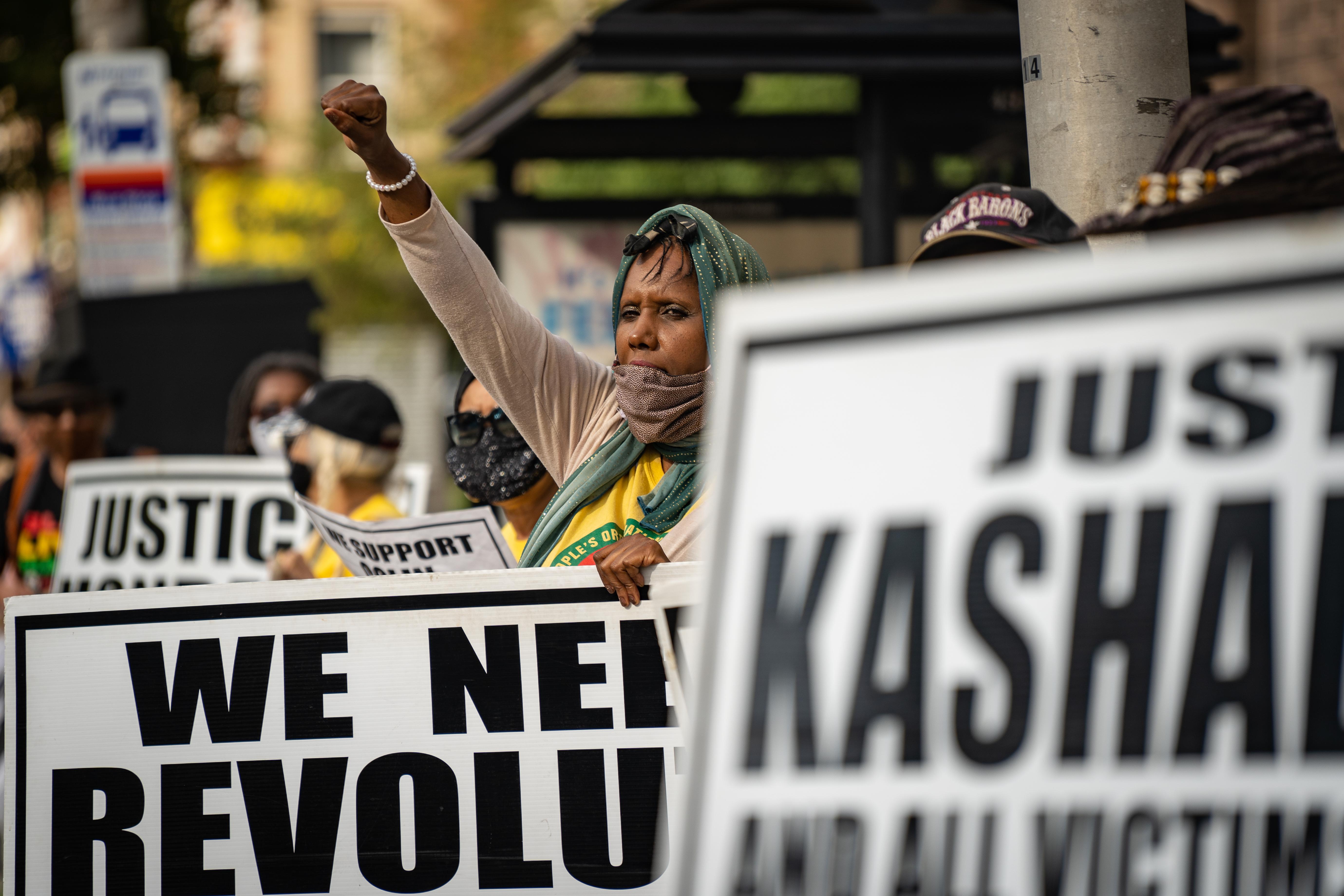 A woman with a sign raises her fist as a crowd gathers at a People's Organization for Progress rally to protest police brutality on August 17, 2020 in Newark, NJ.