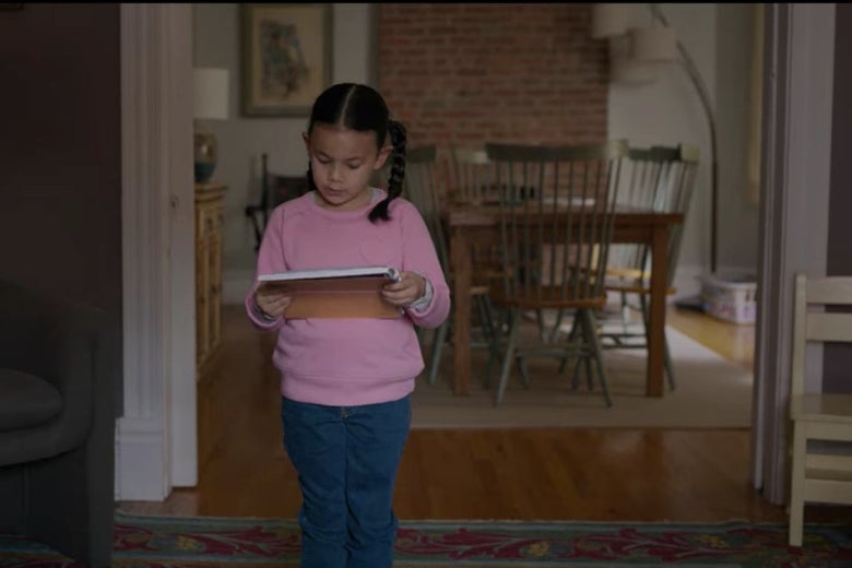 Ju Ju stands up holding a book in front of the dining room.