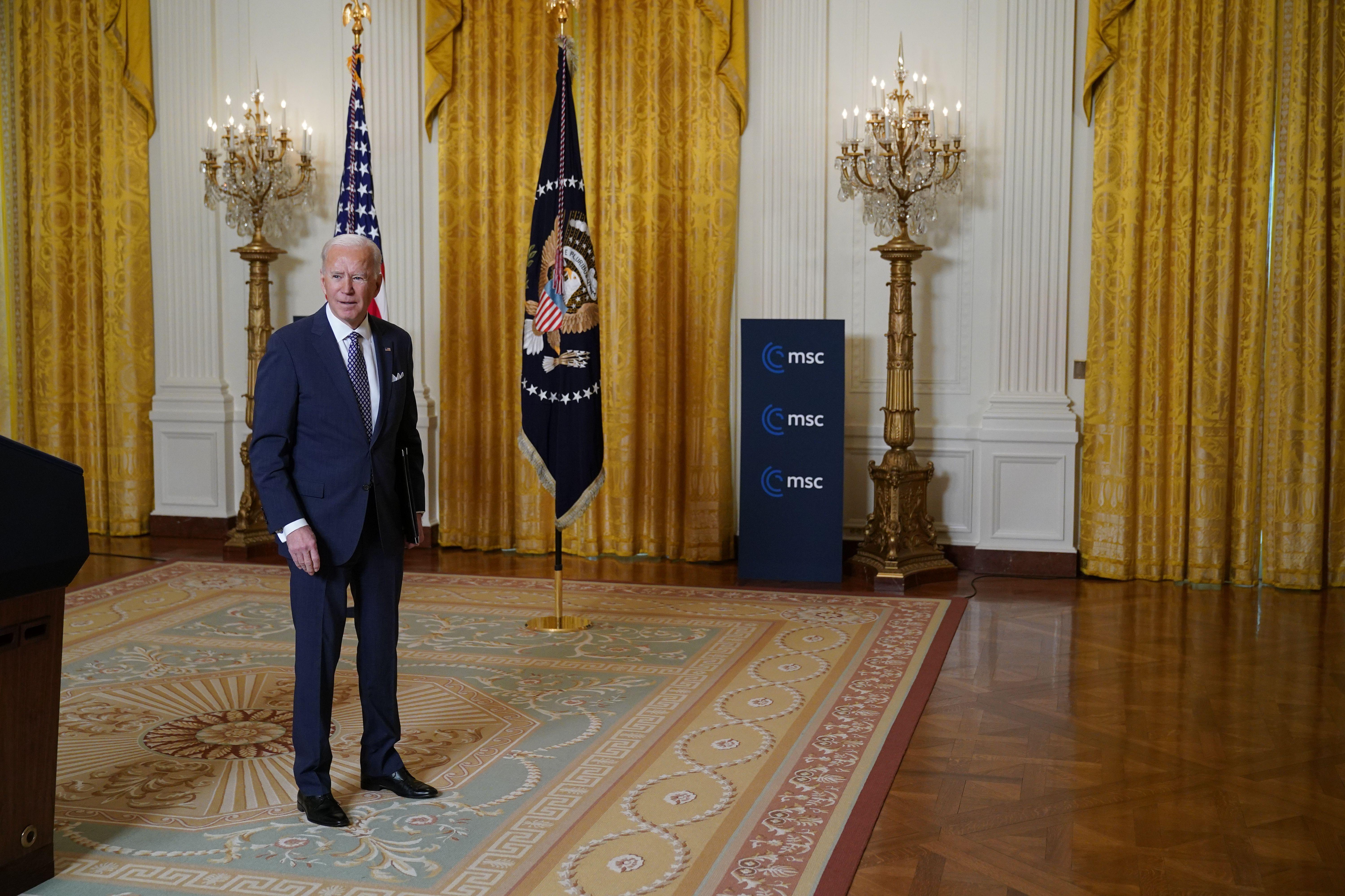 Biden stands in the East Room of the White House.