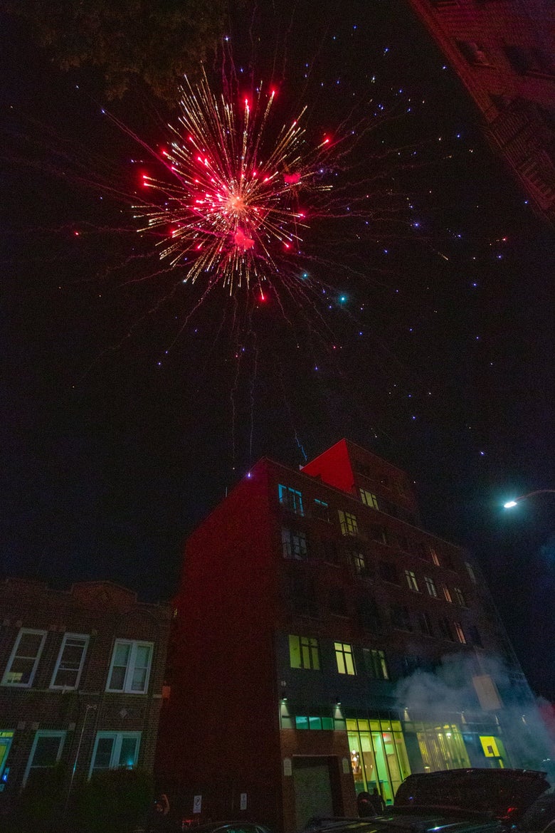 A large red firework explodes over an apartment building in Brooklyn New York
