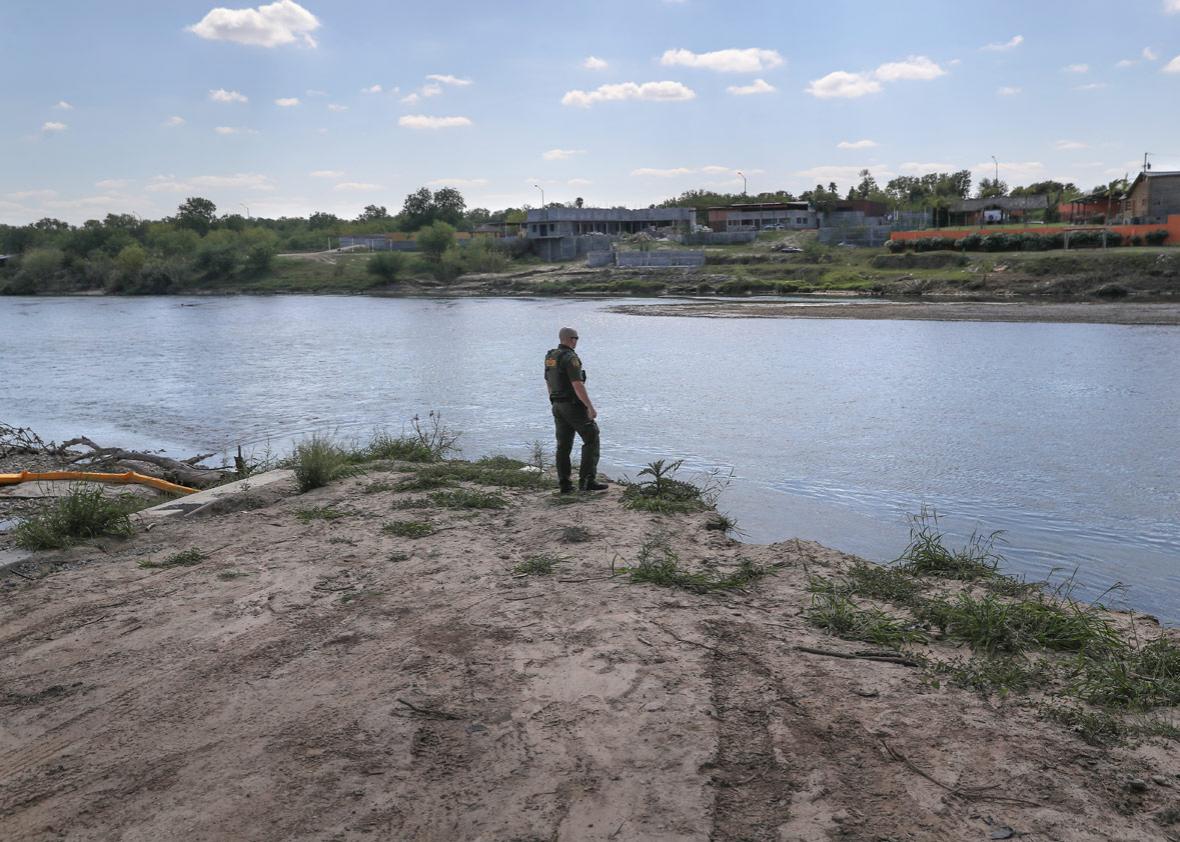 A U.S. Border Patrol agent looks into Mexico from the bank of the Rio Grande at the U.S.-Mexico border.