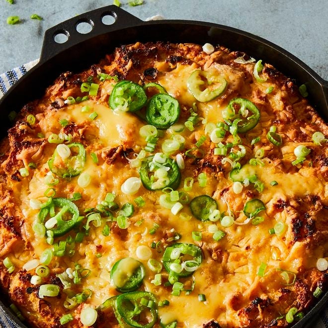 Cornbread strata topped with cheddar, scallions, and jalapeños, in a cast-iron skillet