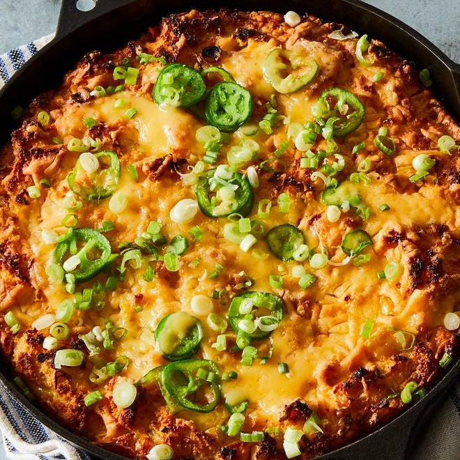 Cornbread strata topped with cheddar, scallions, and jalapeños, in a cast-iron skillet