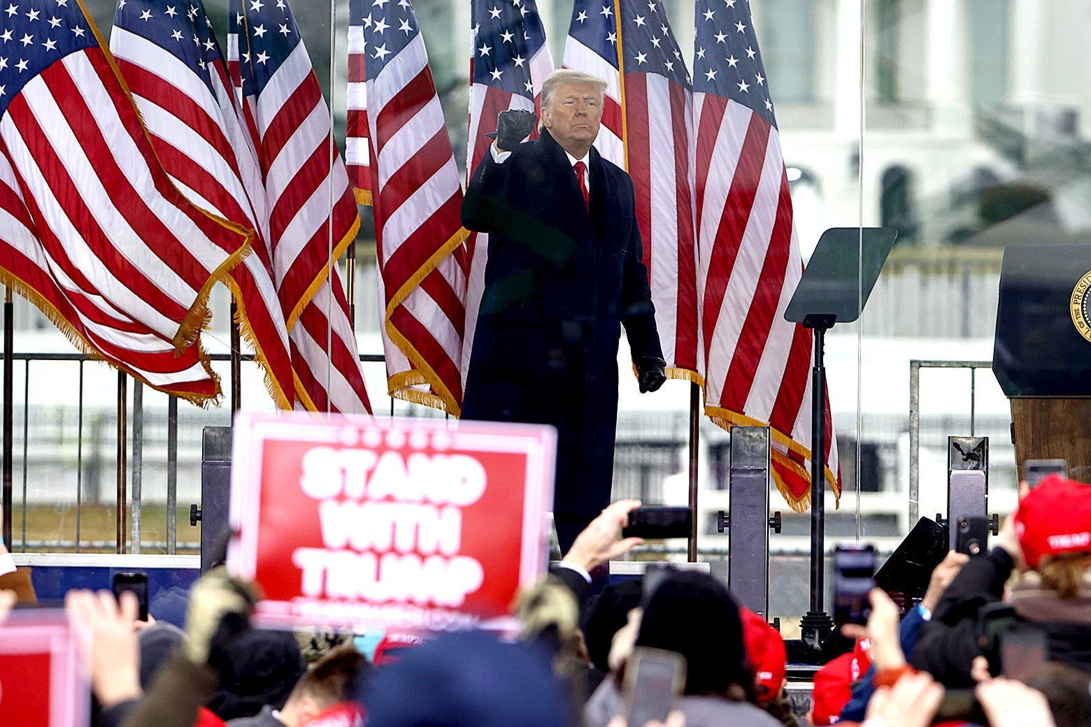 Donald Trump, on a stage with American flags, pumps his fist for protesters.