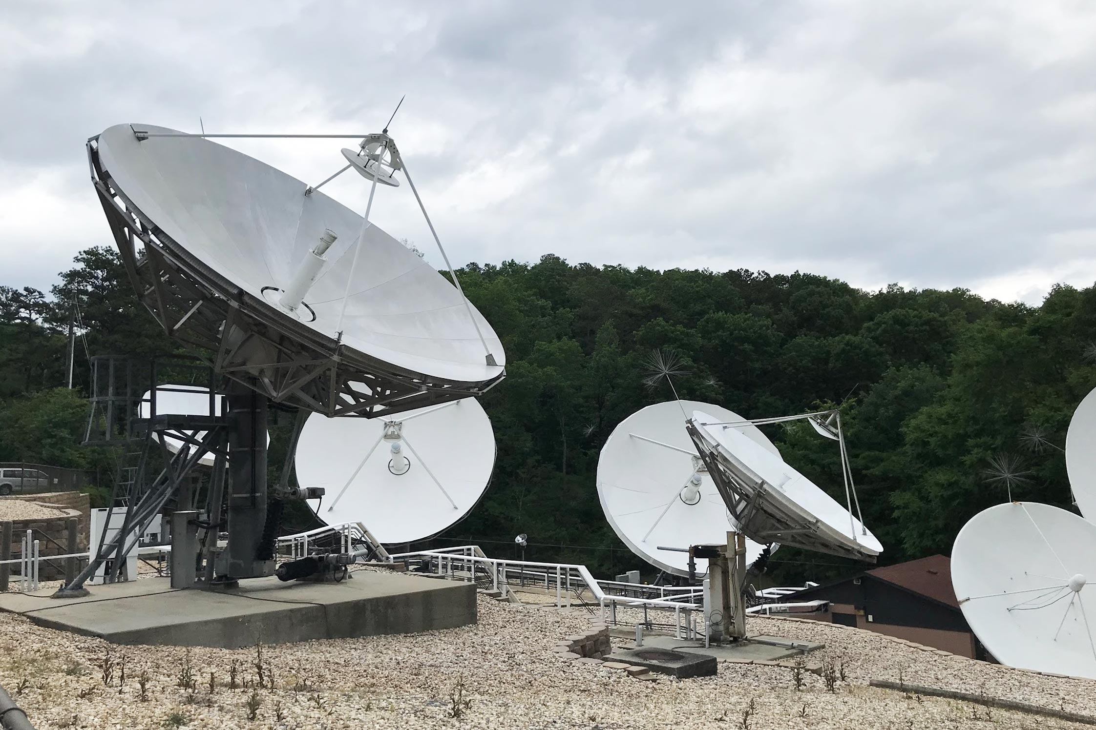 An array of satellite dishes with trees in the background