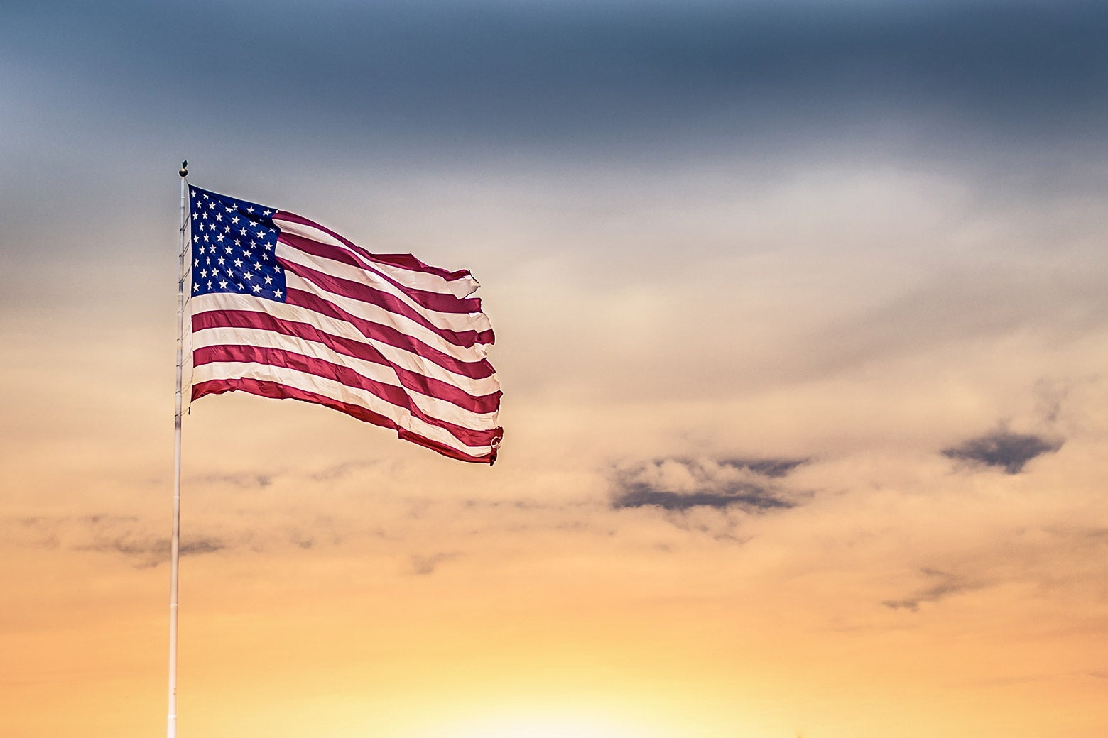 A U.S. flag is seen waving against a sunset.