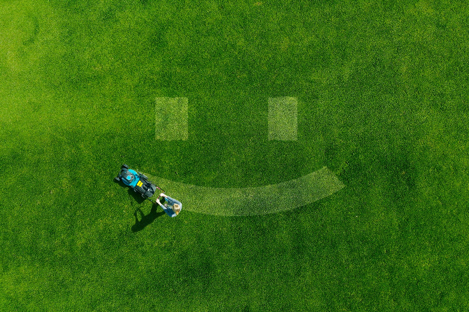 A smiley face shape being mowed into a lush green lawn.