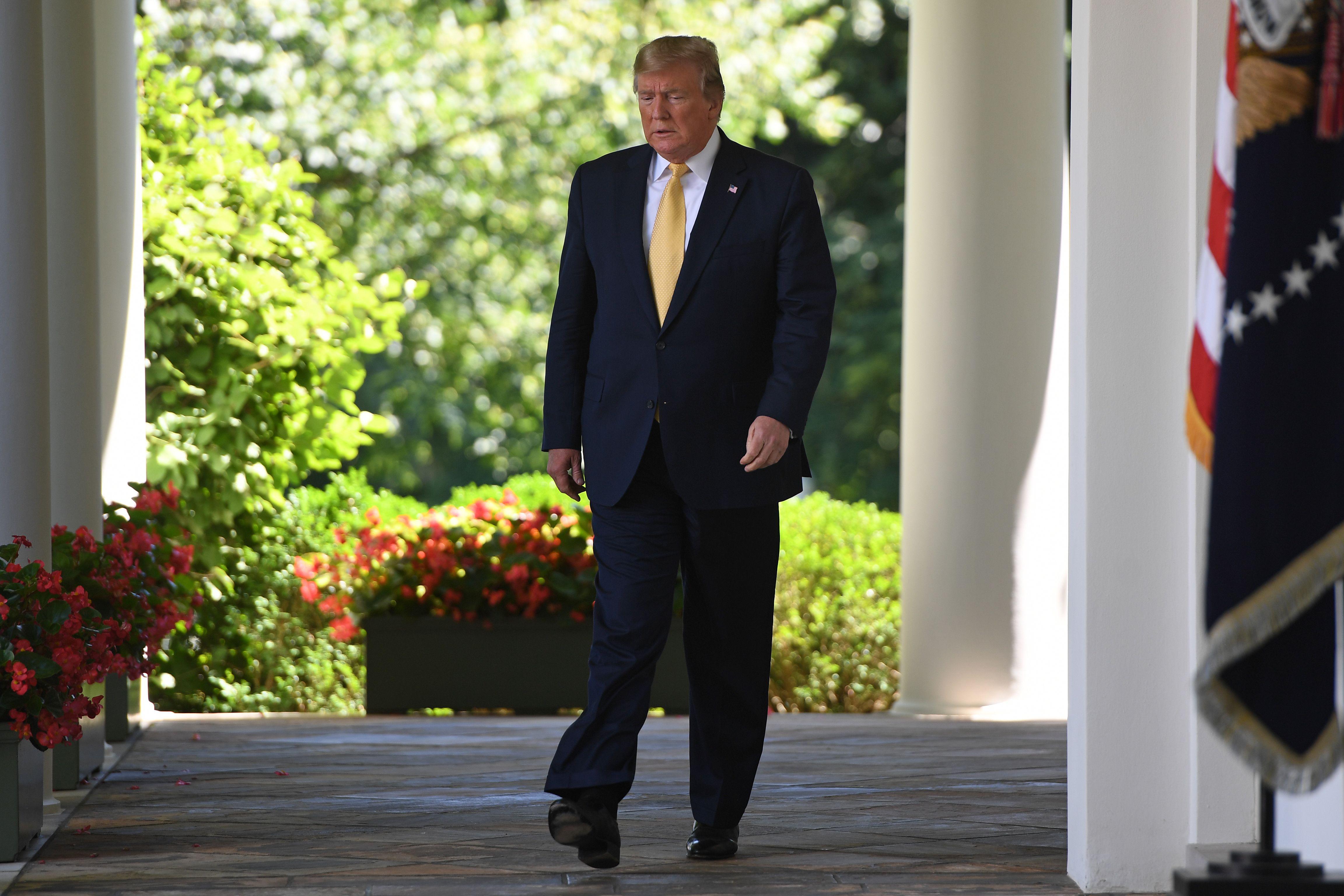 President Donald Trump walks to the Rose Garden of the White House.