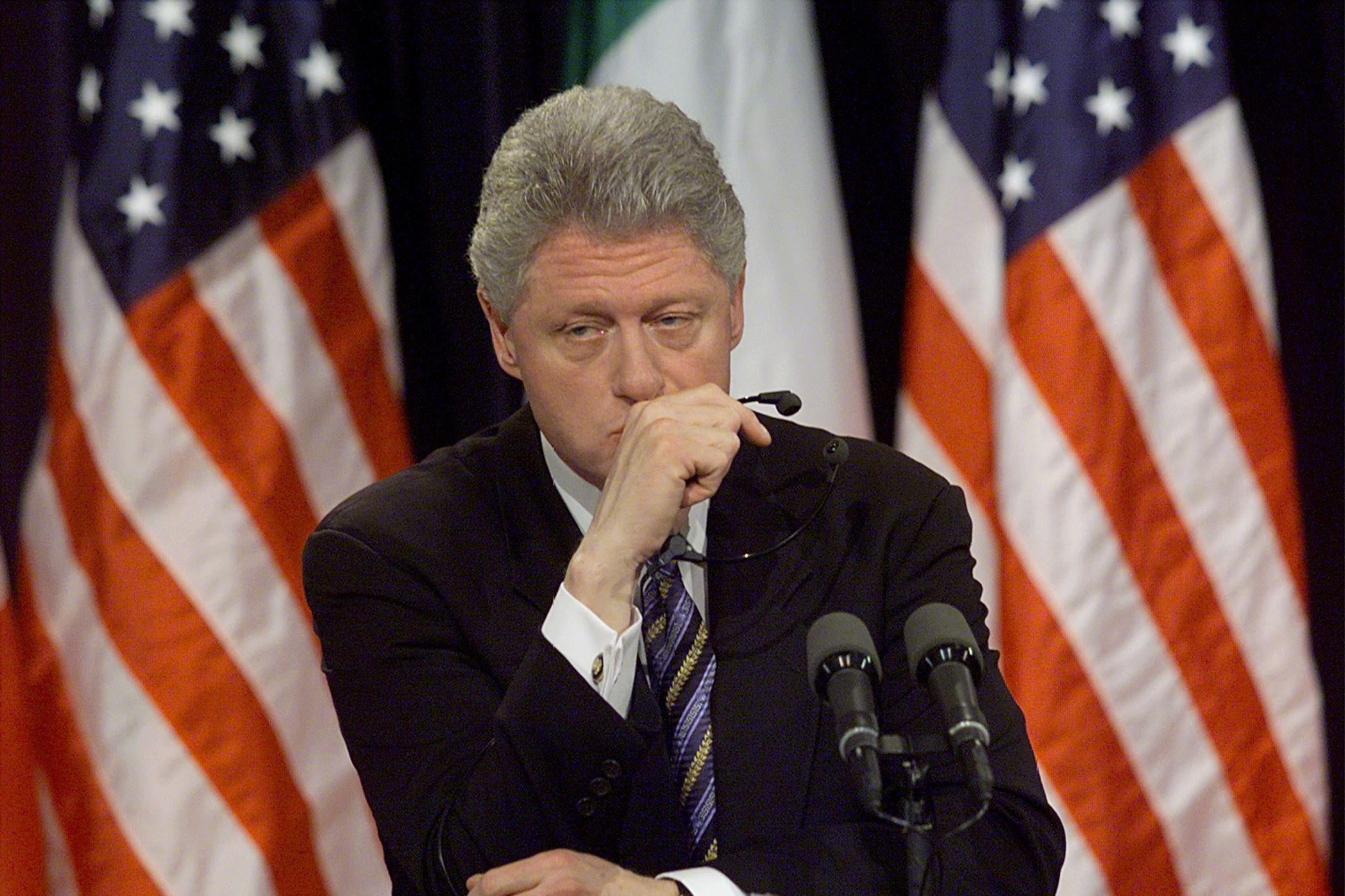 Bill Clinton looking somber in front of a microphone.