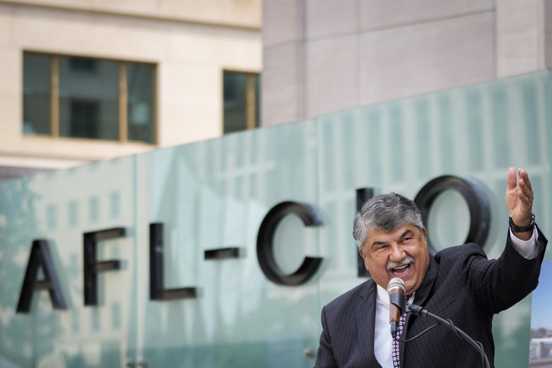 Richard Trumka speaks into a mic and gesticulates in front of a building that reads "AFL-CIO."