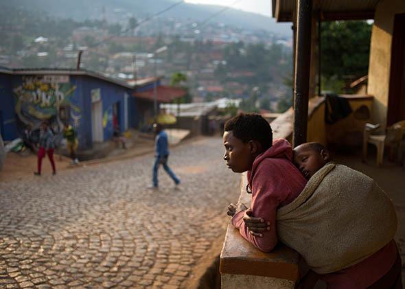 A woman stands on her porch at a suburb set on a hill overlooking Kigali, Rwanda, on March 13, 2014.