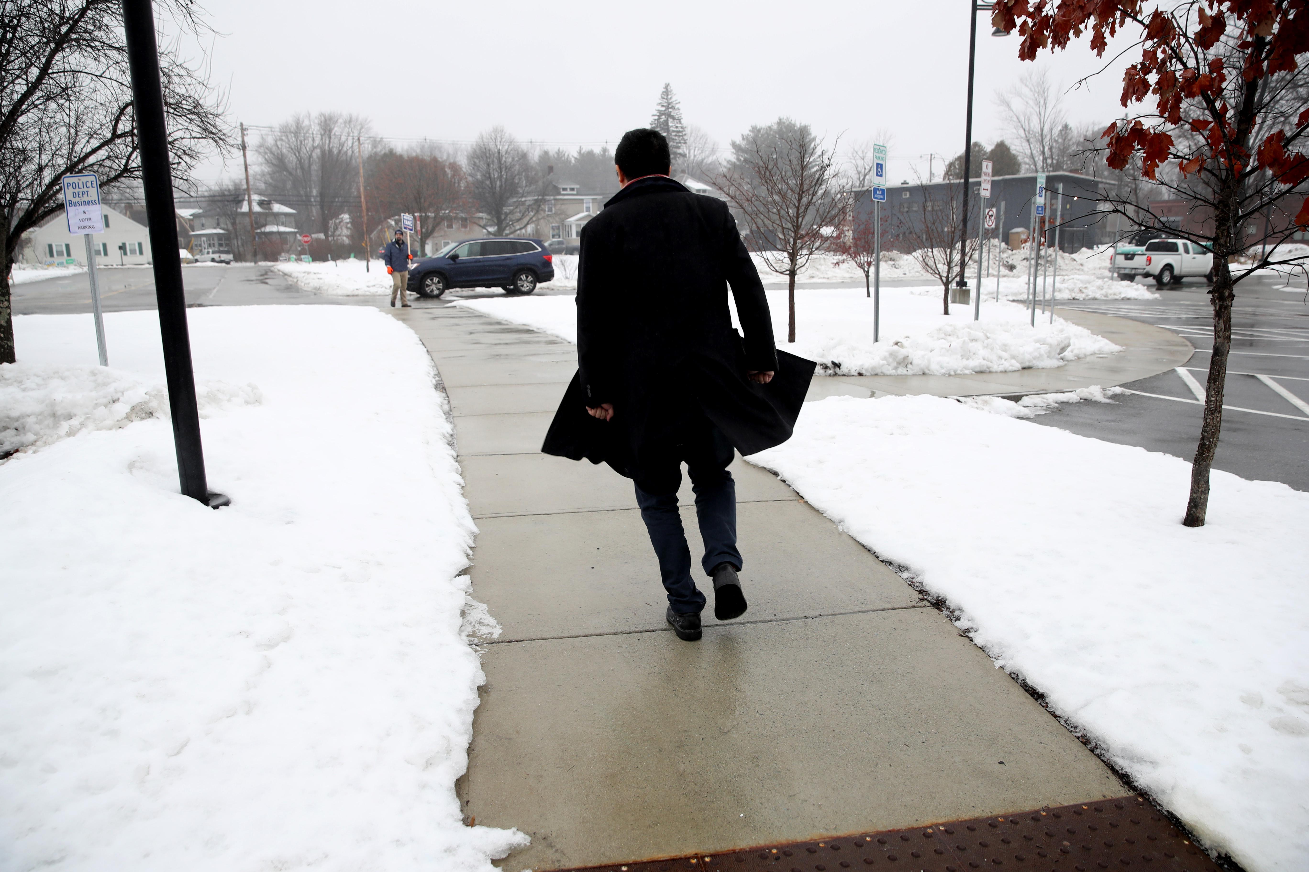 Andrew Yang walks alone on a snowy sidewalk