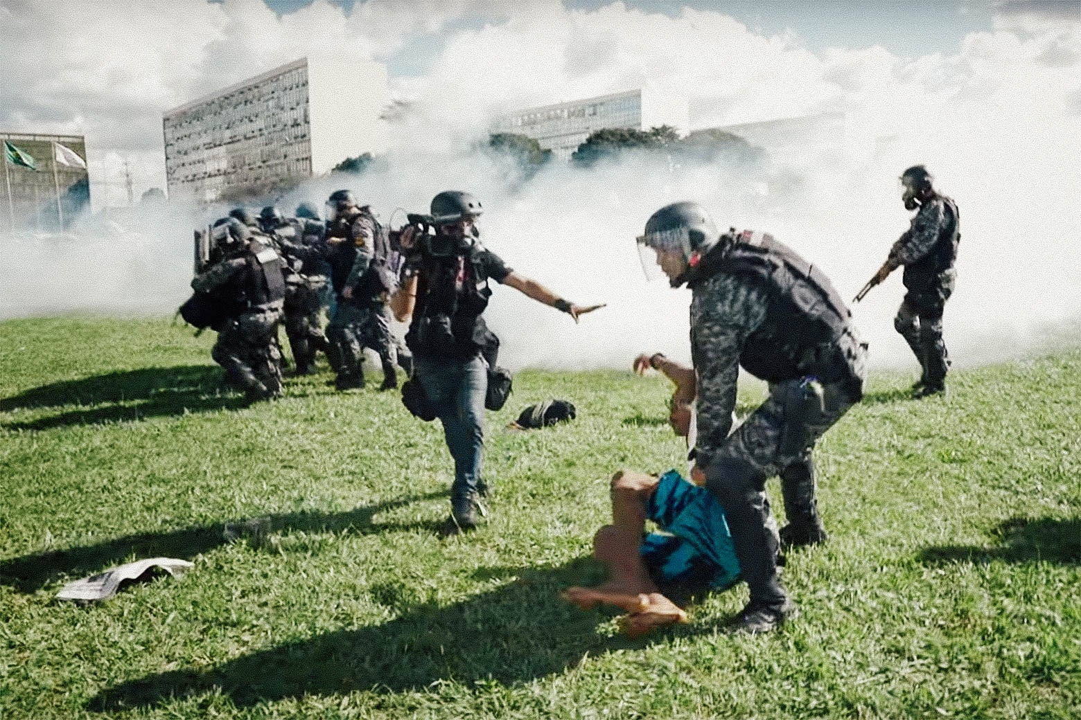 In this still from The Edge of Democracy, armed law enforcement or military deploy crowd control gas on a protest. In the foreground, one officer is gripping a fallen citizen.
