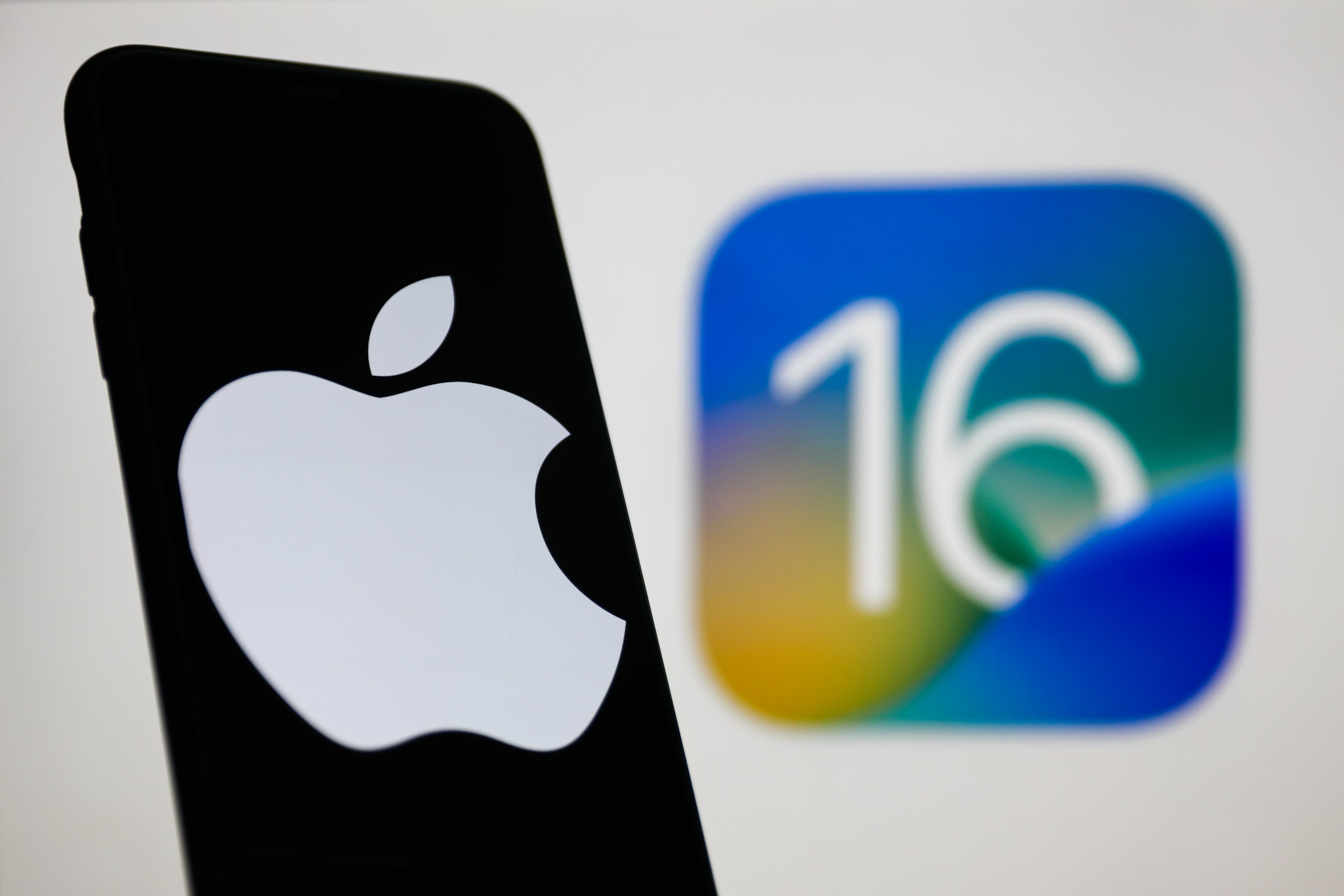 An iPhone with the new iOS 16 logo in the background