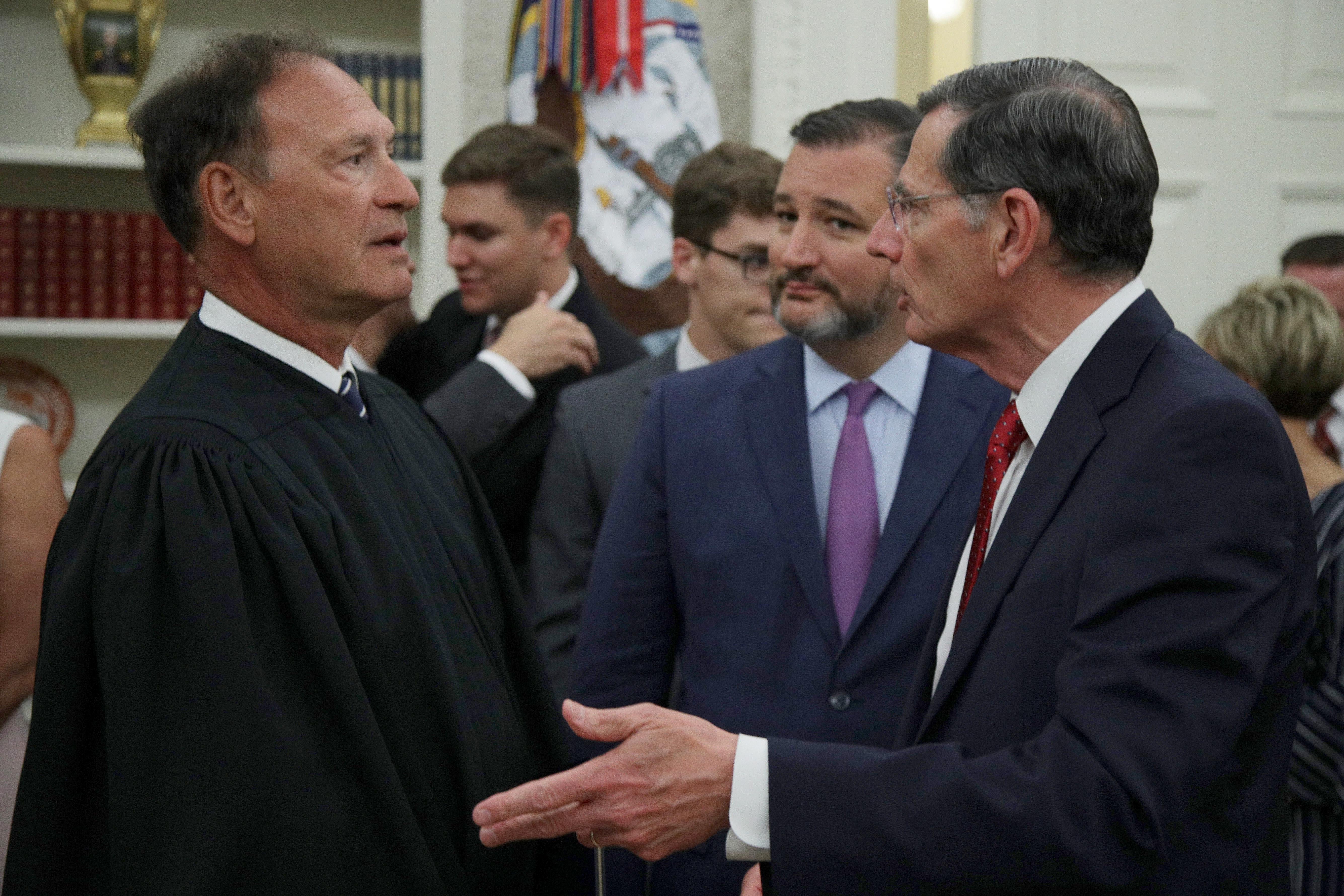 Alito in his robes standing among people mingling in the Oval Office