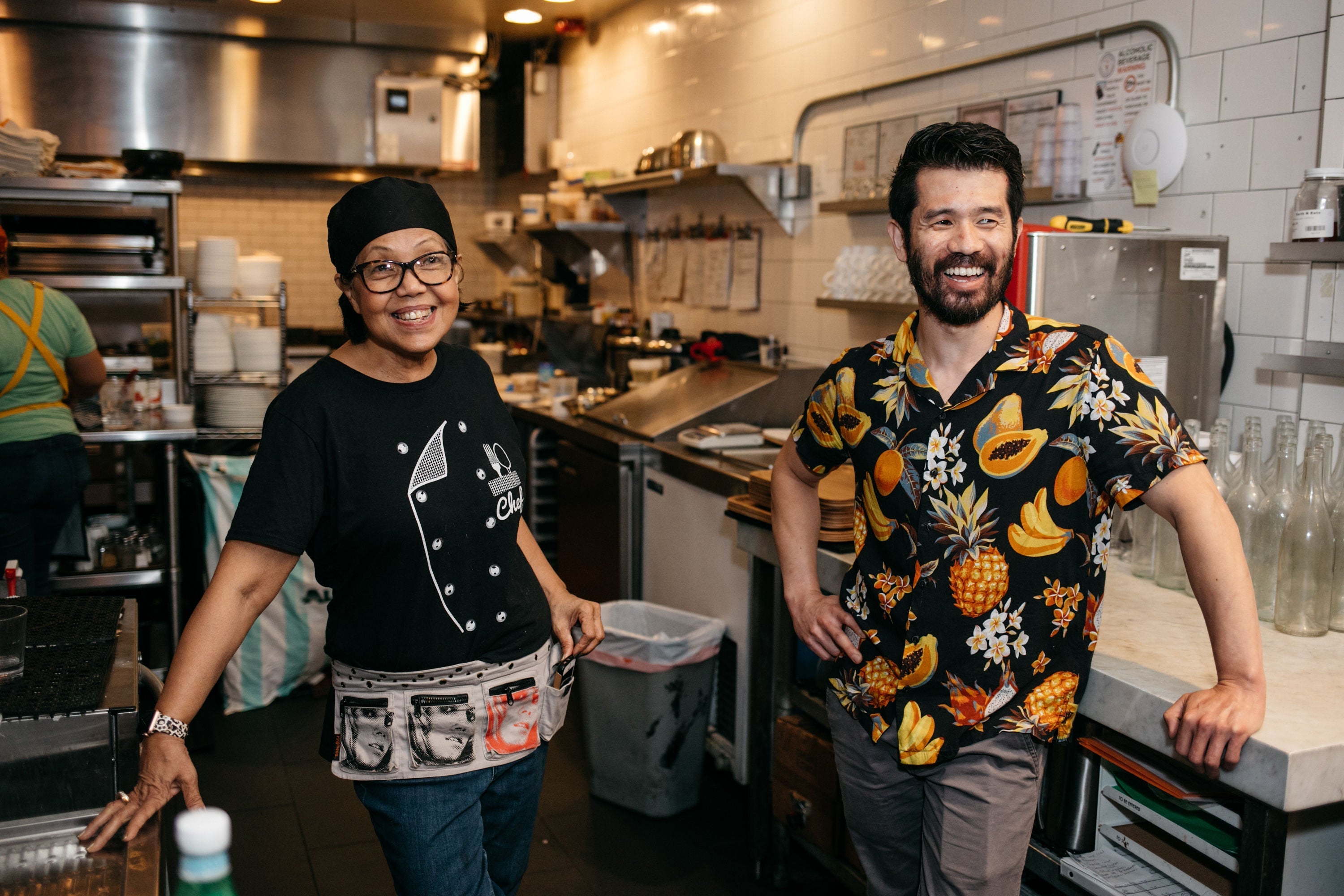 Two people smiling in a restaurant kitchen.