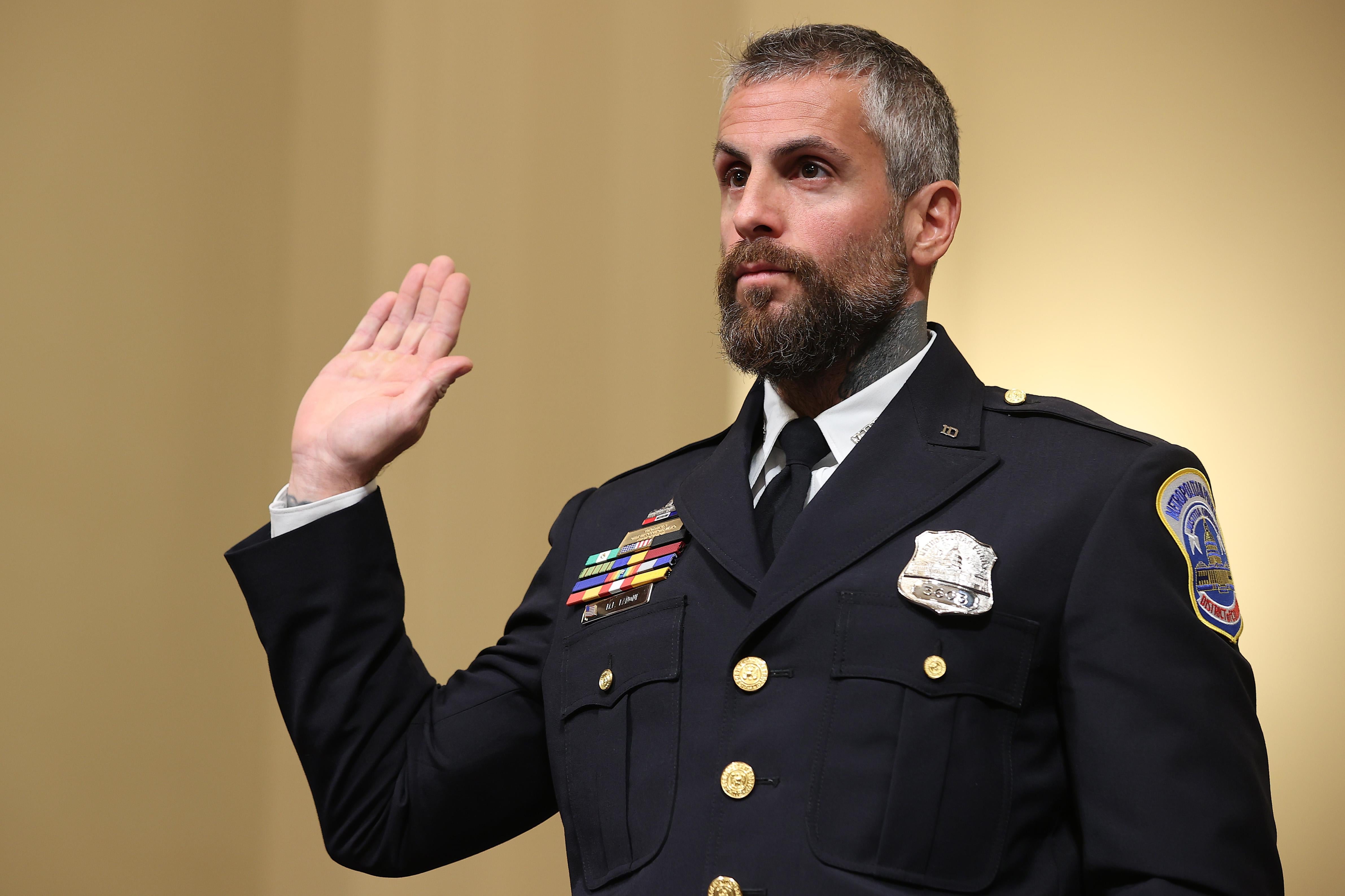In his officer uniform, Fanone raises his right hand to swear to tell the truth.