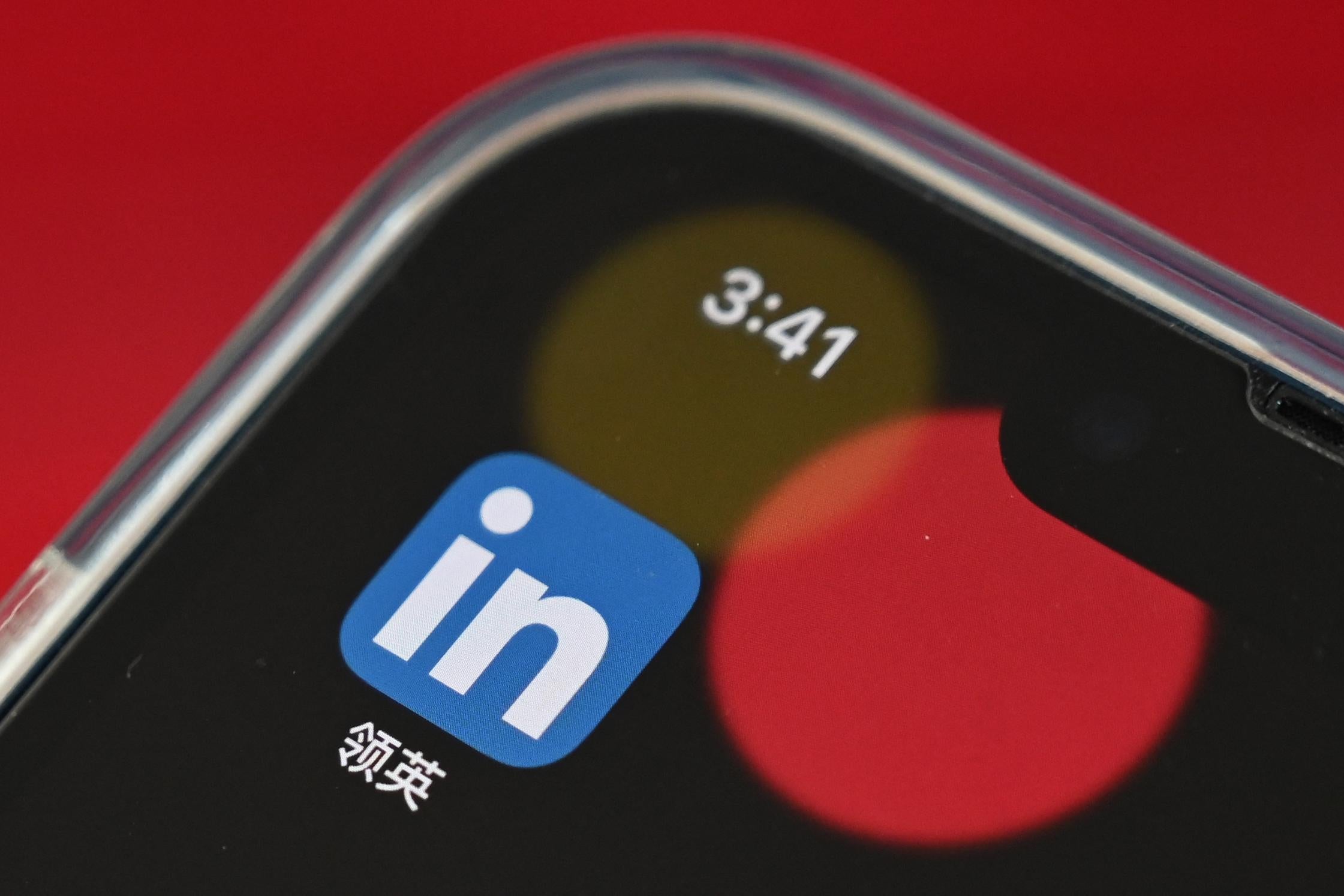 The LinkedIn logo, Chinese characters, and a red dot in the upper left-hand corner of a smartphone.