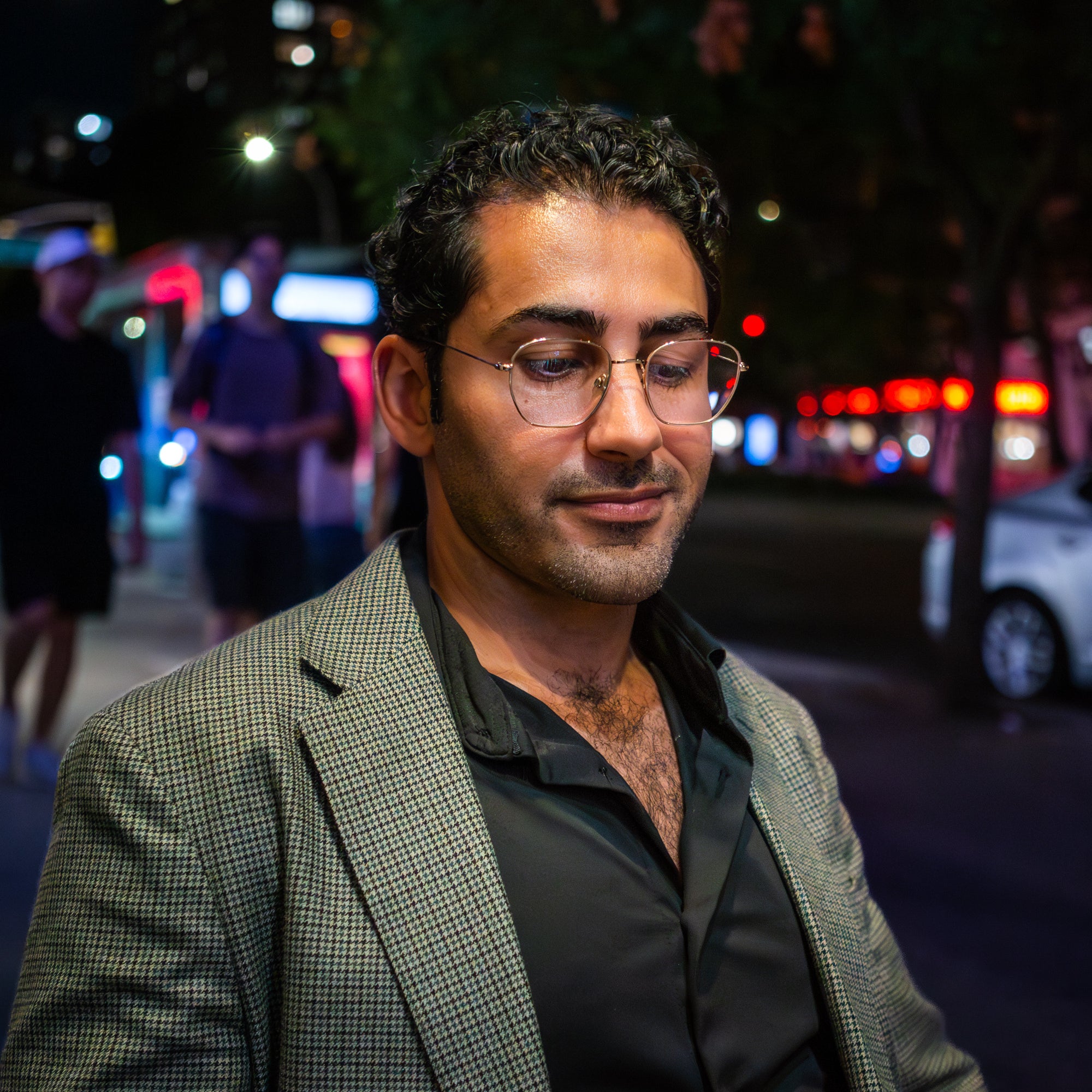 Mohsen Mahdawi smiles and looks down, from on the sidewalk in New York.