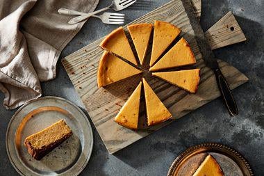 Slices of orange cheesecake on a cutting board with two slices nearby on plates.