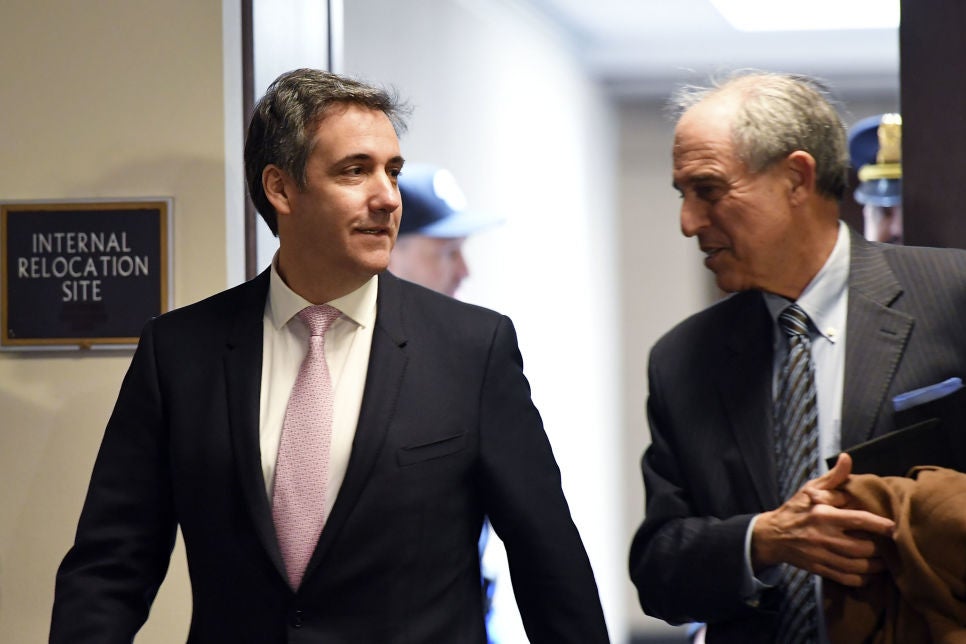 A smiling Cohen converses with Davis as they walk down a hallway.