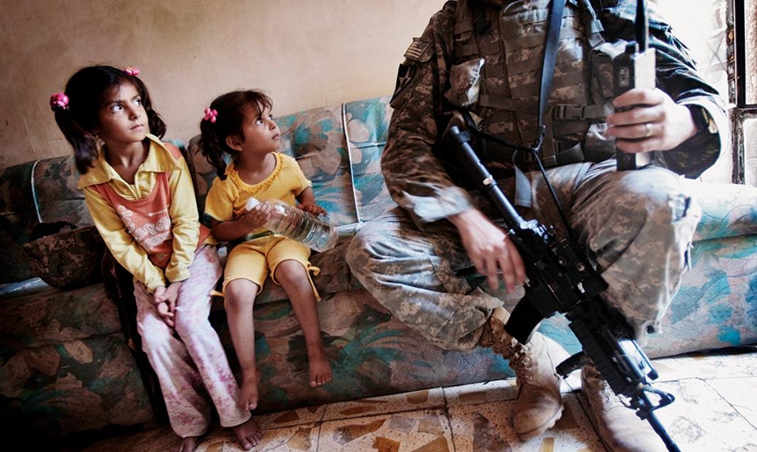 Two Iraqi girls look at Staff Sgt. Nick Gibson while he canvasses the tense Dora neighborhood of Baghdad on June 21, 2007. U.S. soldiers canvased their areas almost every day, attempting to get to know the residents and find insurgents.