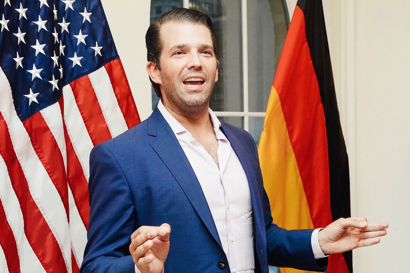 Donald Trump Jr. in front of American and German flags.