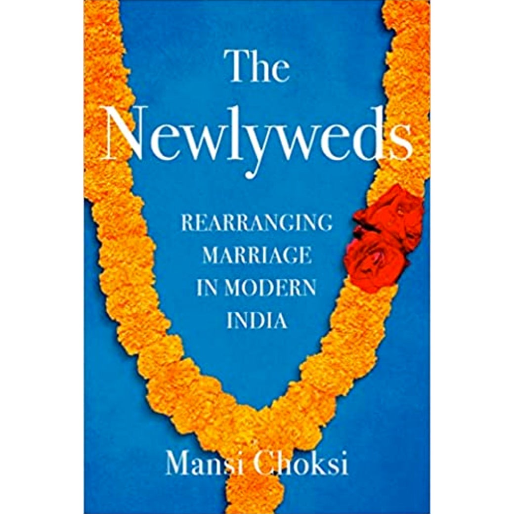 Book jacket showing title, subtitle, and author over a traditional orange wedding garland with two red roses attached on the the right side of it