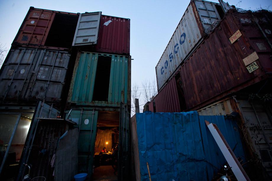 A child (bottom) does homework inside a shipping container serving as his accommodation, in Shanghai March 4, 2013. The containers, which house different families, were set up by the landlord, who charges a rent of 500 yuan ($ 80) per month for each container. 
